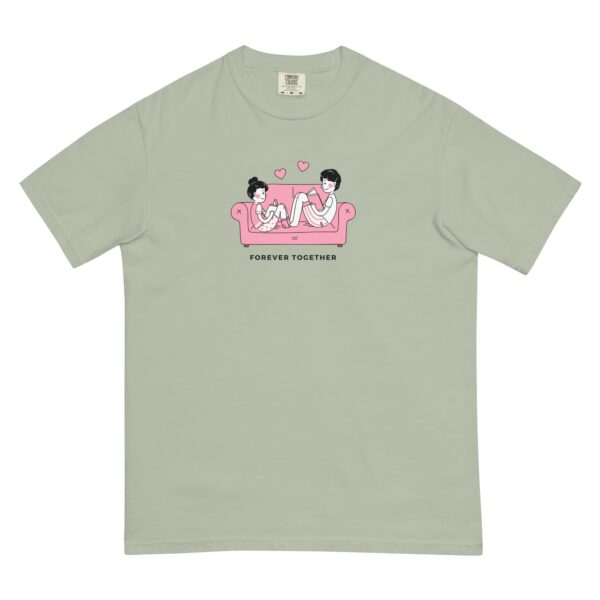 A light green Cute Forever Together unisex t-shirt showcases a cartoon of a couple in pajamas on a pink sofa, each with a game controller. Two hearts float above them.